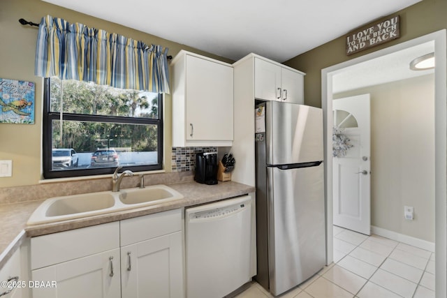 kitchen with light tile patterned flooring, sink, stainless steel fridge, white dishwasher, and white cabinets