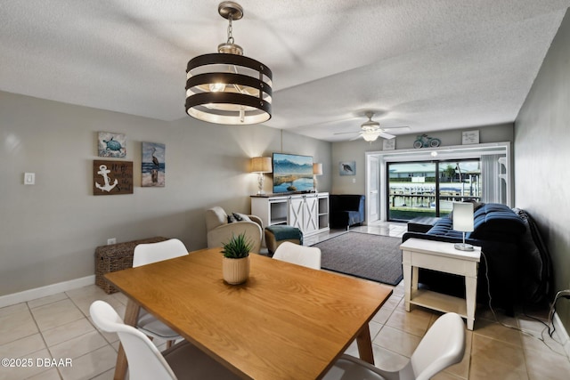 tiled dining room featuring ceiling fan with notable chandelier and a textured ceiling