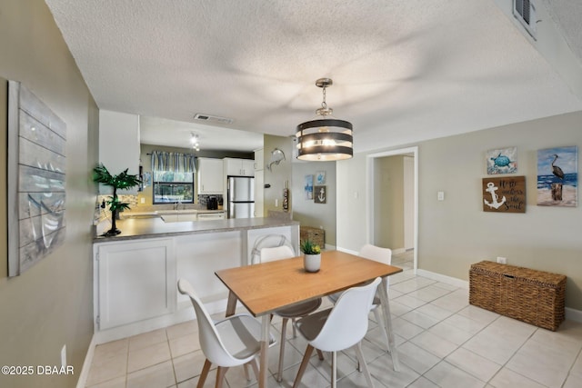 tiled dining room featuring sink and a textured ceiling