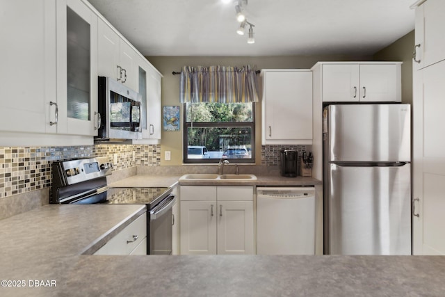 kitchen with sink, backsplash, white cabinets, and appliances with stainless steel finishes