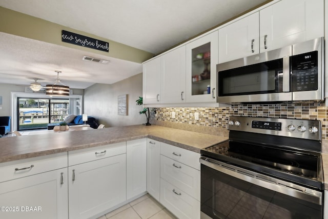 kitchen with tasteful backsplash, light tile patterned floors, stainless steel appliances, and white cabinets