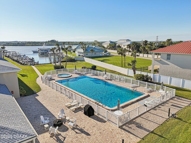 view of pool with a patio area, a water view, a hot tub, an outdoor fire pit, and a yard