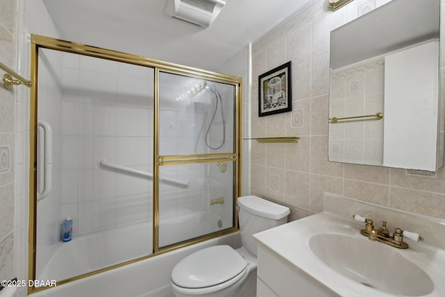 full bathroom featuring tile walls, vanity, shower / bath combination with glass door, and toilet