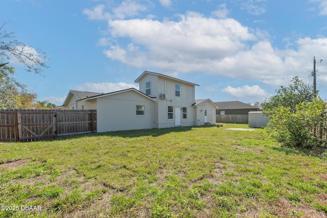 rear view of property featuring a yard, an outdoor structure, and a fenced backyard