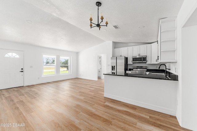 kitchen with stainless steel appliances, visible vents, white cabinets, open shelves, and dark countertops