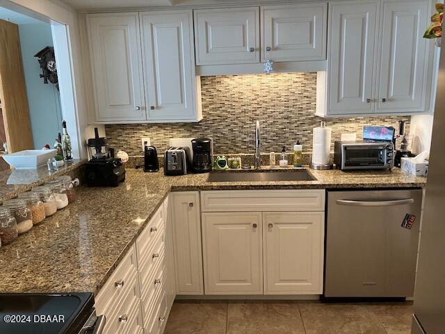 kitchen with sink, white cabinets, stainless steel dishwasher, backsplash, and light tile patterned flooring