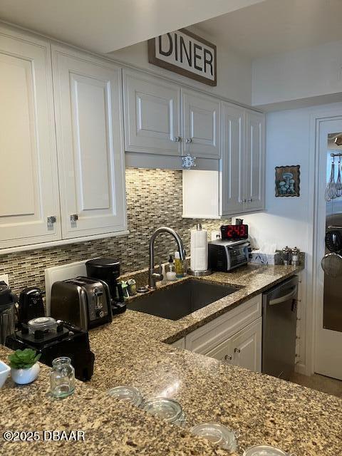 kitchen featuring tasteful backsplash, sink, white cabinets, and stainless steel dishwasher