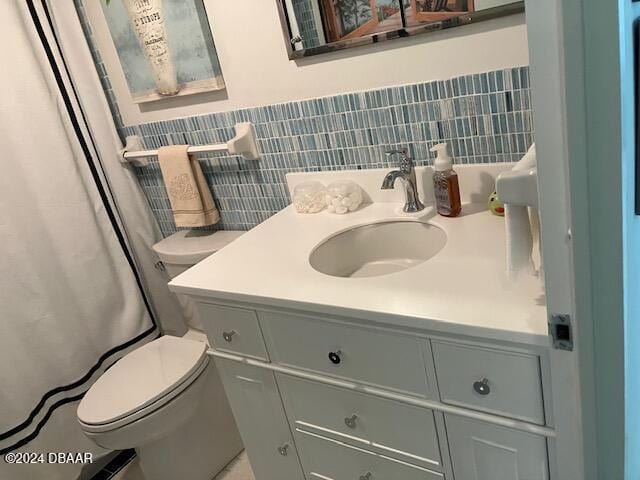 bathroom with a shower with shower curtain, vanity, toilet, and decorative backsplash