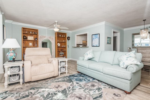 living room with ceiling fan, crown molding, a textured ceiling, and light wood-type flooring