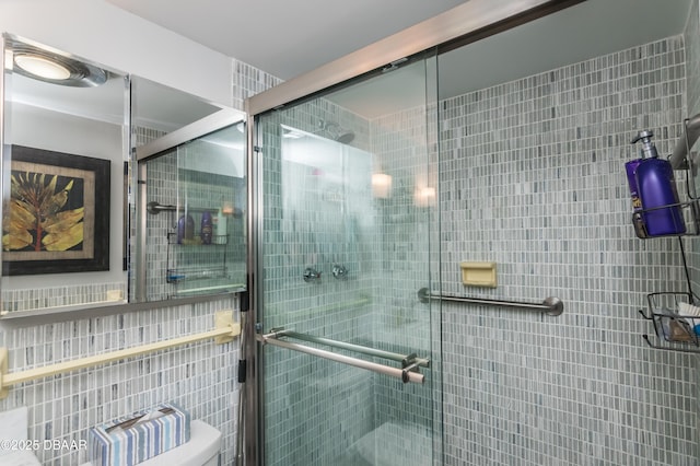 bathroom featuring toilet and a shower with shower door