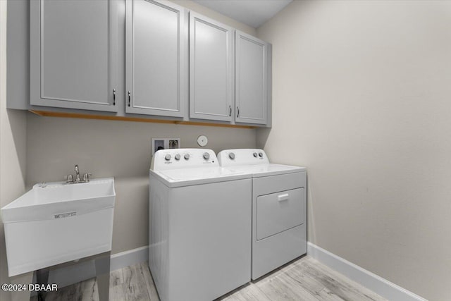 clothes washing area featuring cabinets, light wood-type flooring, sink, and washing machine and clothes dryer