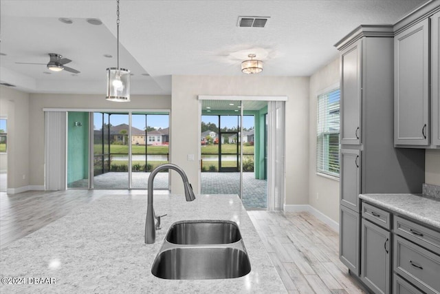 kitchen featuring ceiling fan, gray cabinets, pendant lighting, light hardwood / wood-style floors, and sink