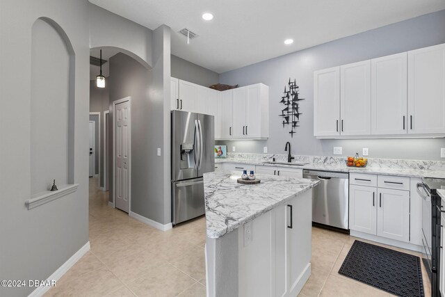 kitchen with stainless steel appliances, sink, a kitchen island, white cabinets, and pendant lighting