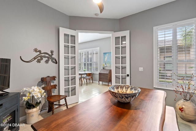 tiled dining room featuring ceiling fan and french doors