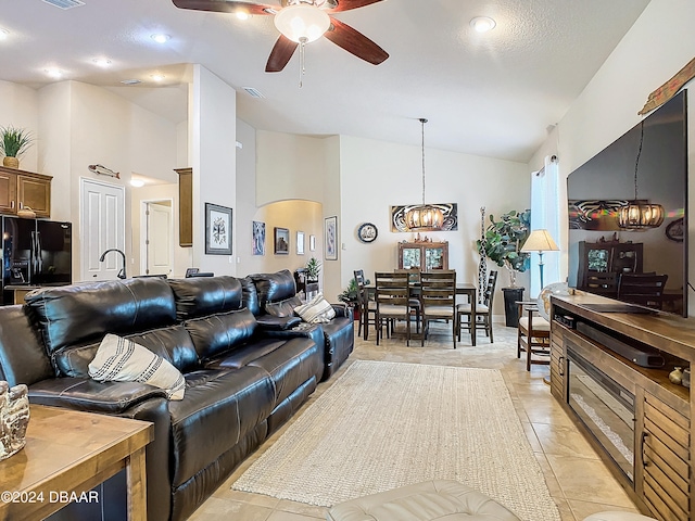 living room with high vaulted ceiling, light tile patterned floors, and ceiling fan with notable chandelier