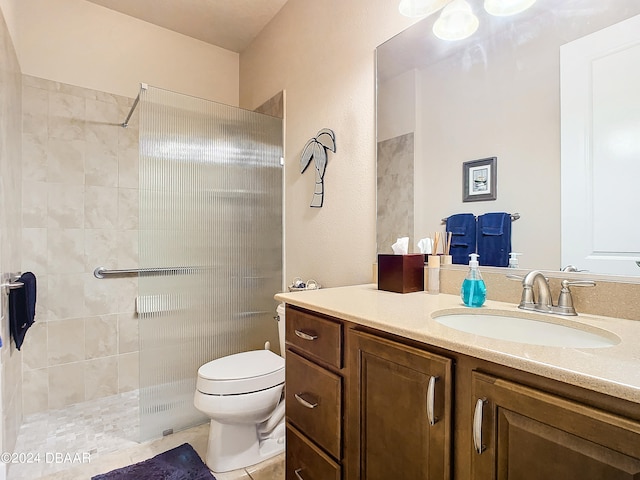 bathroom with toilet, tile patterned flooring, vanity, and a tile shower