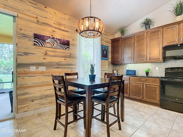 dining area with wood walls, a chandelier, vaulted ceiling, and light tile patterned floors