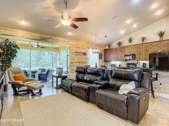 tiled living room with high vaulted ceiling, wooden walls, and ceiling fan with notable chandelier