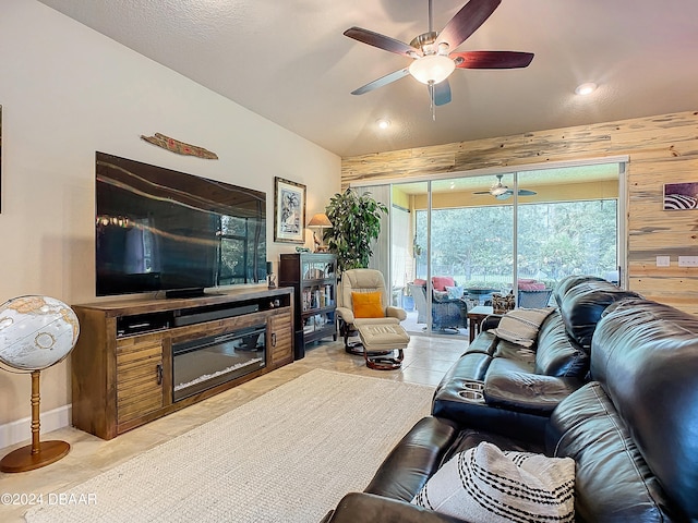 living room featuring wooden walls, ceiling fan, vaulted ceiling, and light tile patterned floors