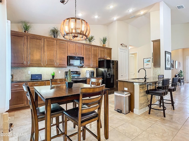 kitchen with black appliances, a breakfast bar area, high vaulted ceiling, hanging light fixtures, and a chandelier