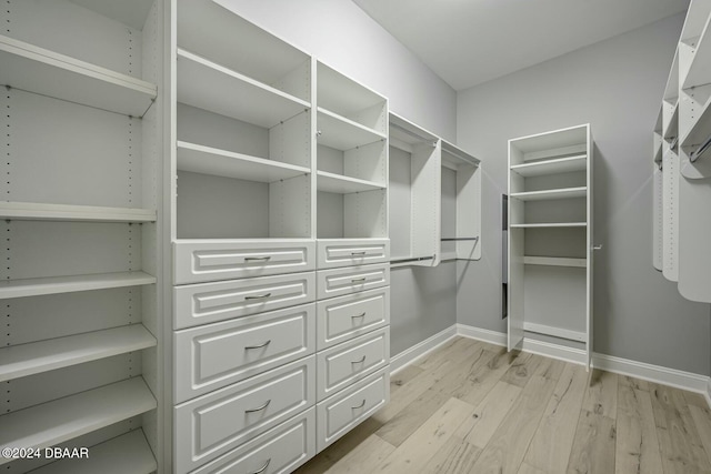 walk in closet with light hardwood / wood-style floors