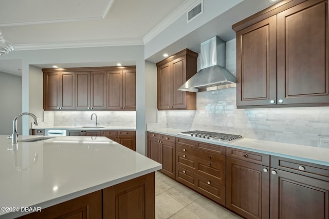 kitchen featuring decorative backsplash, sink, wall chimney range hood, and stainless steel gas cooktop