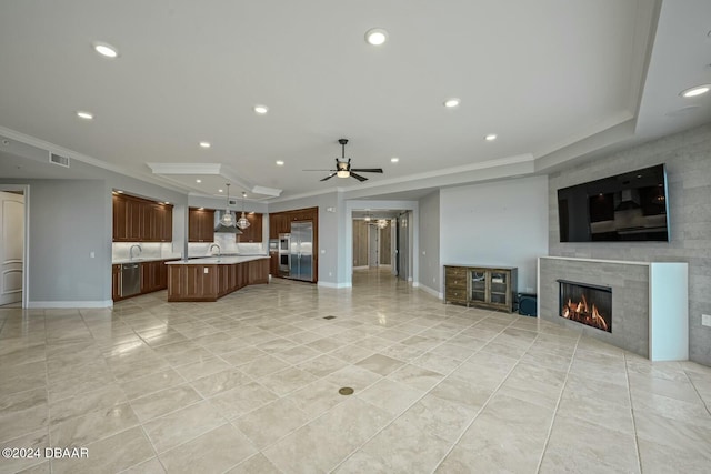 unfurnished living room with a tile fireplace, ceiling fan, sink, and ornamental molding