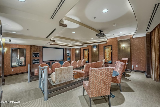 home theater room featuring a tray ceiling and light colored carpet