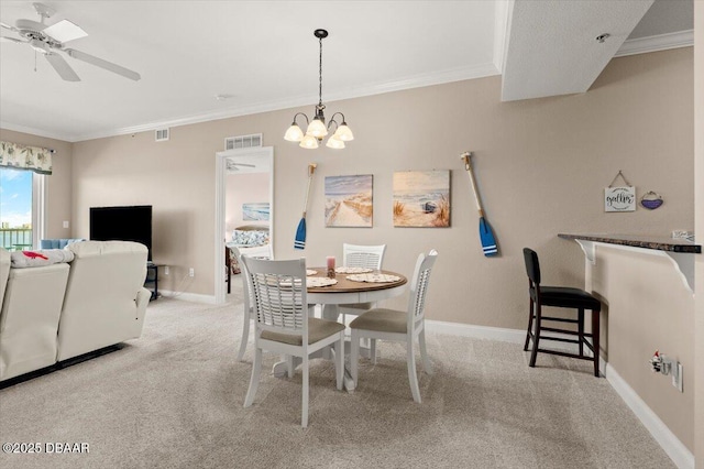 dining area with ceiling fan with notable chandelier, ornamental molding, and light carpet