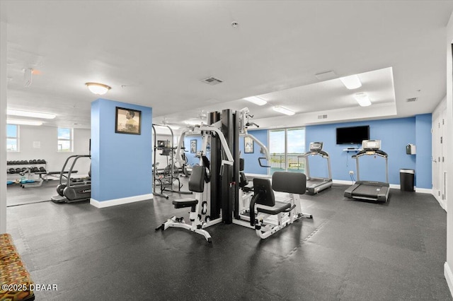 gym featuring a healthy amount of sunlight and a raised ceiling