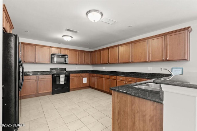 kitchen with dark stone counters, black appliances, light tile patterned floors, sink, and kitchen peninsula