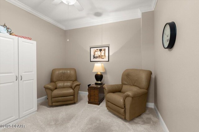 sitting room with ceiling fan, crown molding, and light carpet