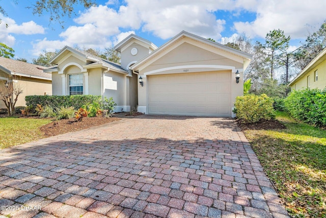 ranch-style house with an attached garage, decorative driveway, and stucco siding