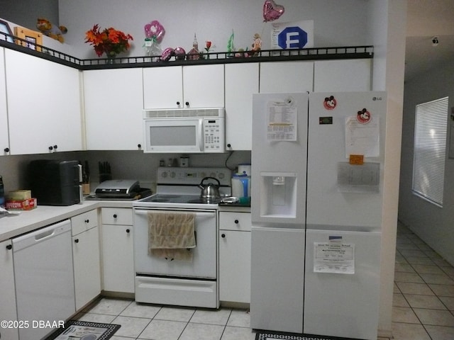 kitchen featuring white appliances, light tile patterned floors, and white cabinets