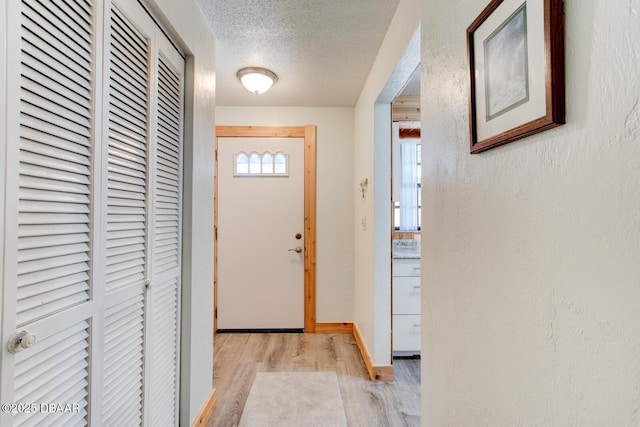 doorway featuring light wood-type flooring and a textured ceiling