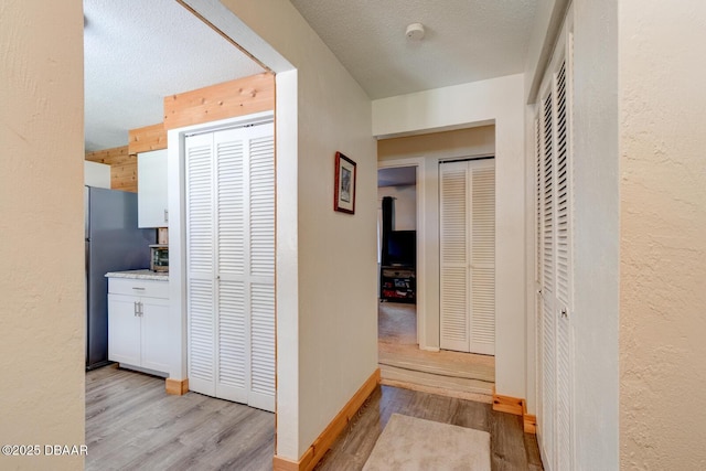 hallway featuring light hardwood / wood-style flooring and a textured ceiling