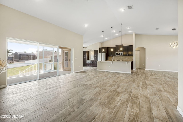 10 Creek Ct, Palm Coast, FL 32137 - unfurnished living room featuring a sink, light wood-style floors, visible vents, baseboards, and arched walkways