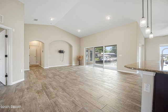 10 Creek Ct, Palm Coast, FL 32137 - unfurnished living room featuring light wood finished floors, arched walkways, lofted ceiling, and baseboards