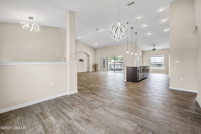 10 Creek Ct, Palm Coast, FL 32137 - unfurnished living room featuring visible vents, baseboards, arched walkways, wood finished floors, and ceiling fan with notable chandelier