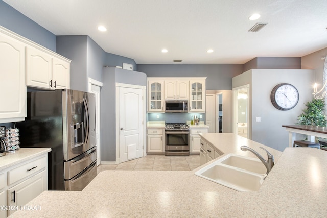 kitchen featuring appliances with stainless steel finishes, light tile patterned floors, white cabinetry, and sink