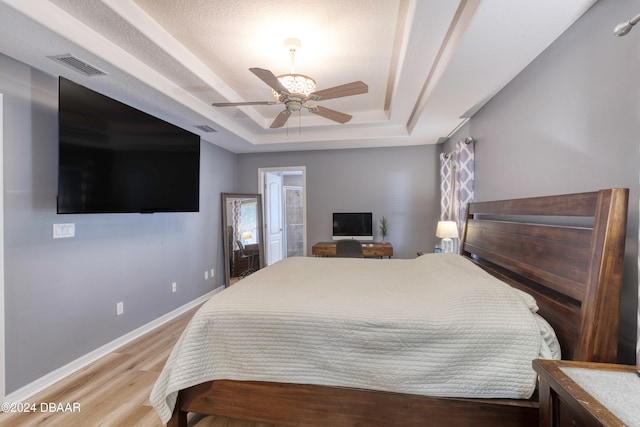 bedroom featuring ceiling fan, a raised ceiling, and wood-type flooring