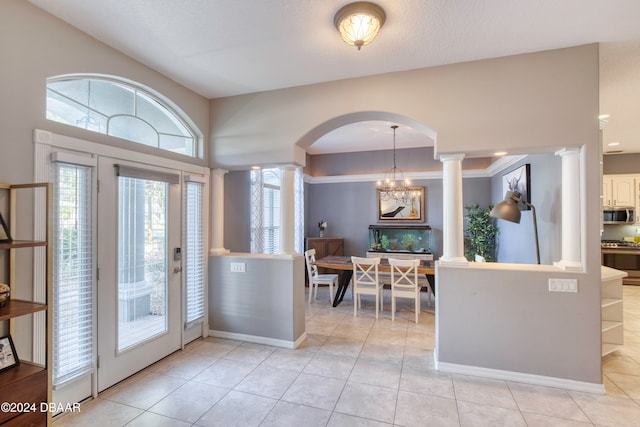 entrance foyer with ornate columns, crown molding, light tile patterned floors, and a notable chandelier