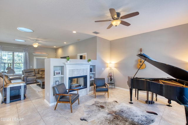 sitting room featuring ceiling fan, light tile patterned flooring, and a tiled fireplace