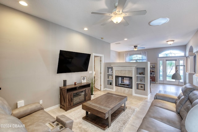 tiled living room with a tile fireplace, ceiling fan, and a textured ceiling