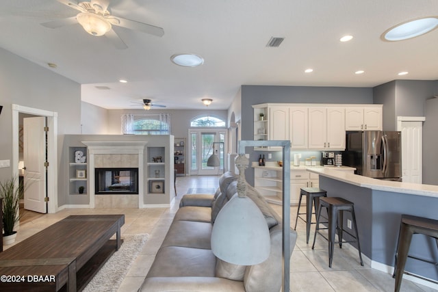 living room with a fireplace, ceiling fan, and light tile patterned flooring