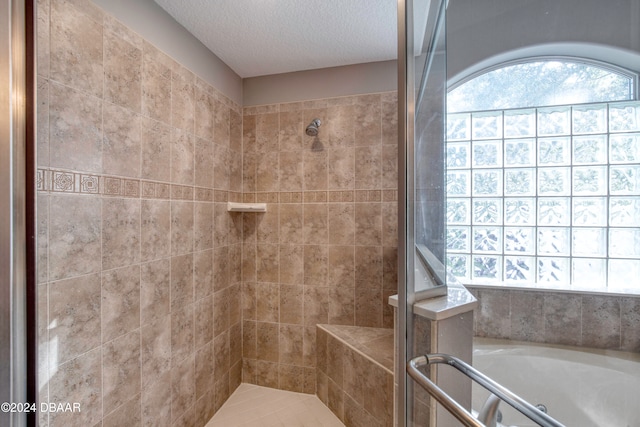 bathroom featuring a textured ceiling and independent shower and bath