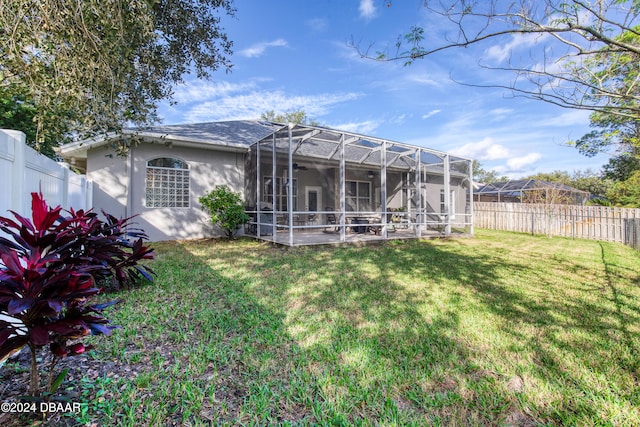 rear view of property with glass enclosure, a patio area, and a lawn