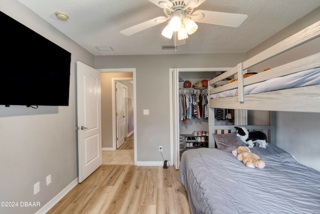 bedroom with a textured ceiling, light wood-type flooring, a closet, and ceiling fan