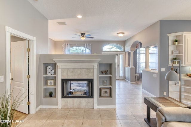 living room featuring a tile fireplace, light tile patterned floors, a textured ceiling, and ceiling fan