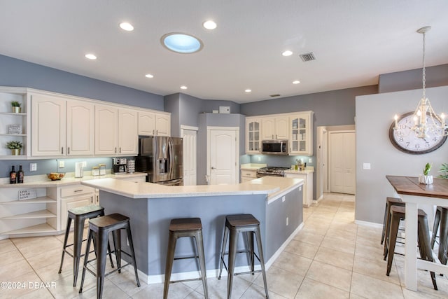 kitchen with a kitchen bar, appliances with stainless steel finishes, white cabinetry, and pendant lighting